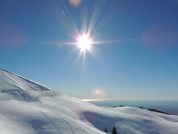 Scenic view of snow covered mountains against sky on sunny day