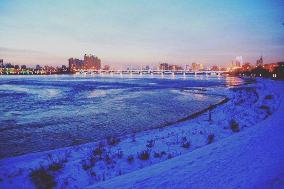 CITY BY RIVER AGAINST SKY DURING WINTER