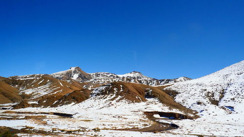 Scenic view of snowcapped mountains against clear blue sky