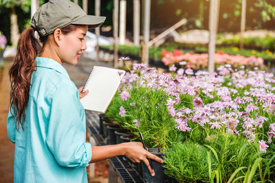 Side view of woman looking at flowering plants