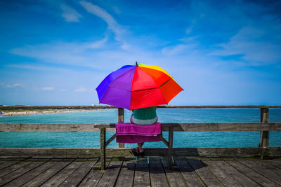 Person with umbrella sitting in front of sea