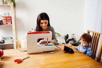 Siblings sitting on table at home