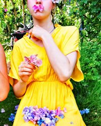 Midsection of woman holding yellow flower