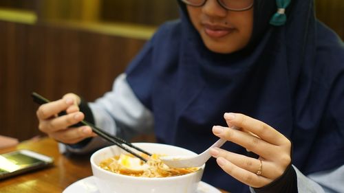 Midsection of man holding ice cream on table in restaurant