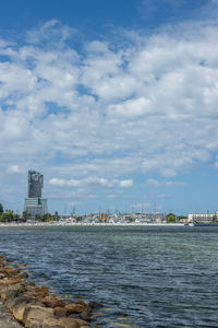 View of buildings by sea against cloudy sky
