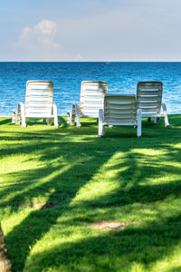 Deck chairs on beach against sky