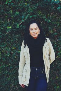 Portrait of smiling mid adult woman standing against plants