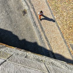 High angle view of man walking on street during sunny day