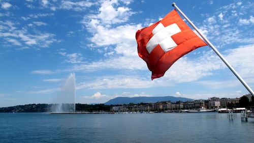 Red flag by water against sky