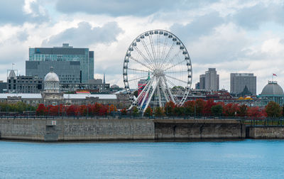 Ferris wheel in city against cloudy sky