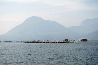 Scenic view of sea by mountains against sky