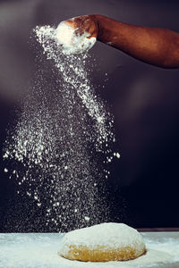 Cropped hand of man blowing water