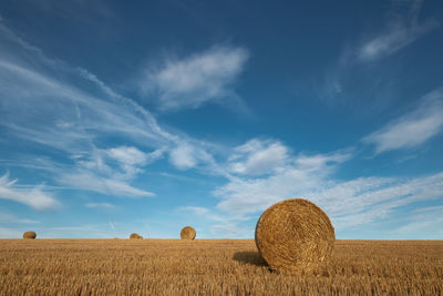 Hay bales on field against sky