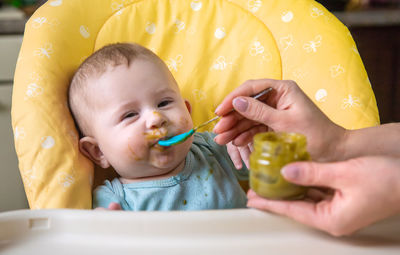 Close-up of boy blowing bubbles while sitting at home