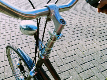 Cropped hand riding bicycle on street during sunny day