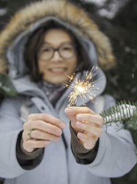 Smiling woman celebrates christmas or new year with sparkler. bengal fire, traditional firework