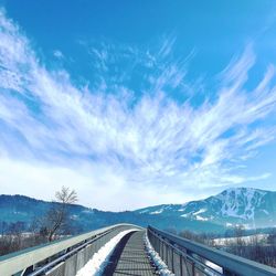 Road leading towards snowcapped mountains against sky