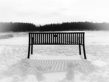 Empty bench on snow field during winter