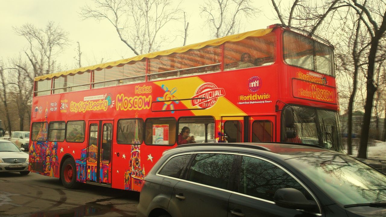 transportation, mode of transport, land vehicle, car, text, yellow, travel, tree, red, western script, street, road, public transportation, bus, communication, on the move, stationary, passenger train, bare tree, outdoors