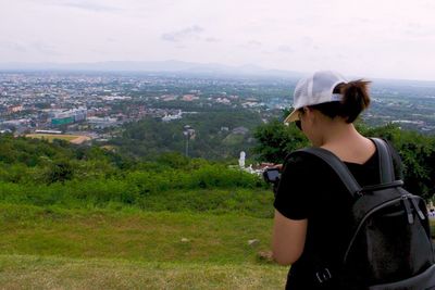 Rear view of woman looking at cityscape against sky