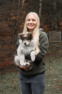 Portrait of smiling young woman holding a finnish lapphund dog puppy