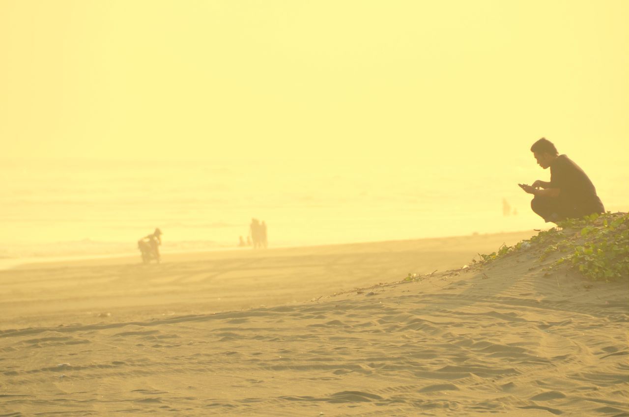 lifestyles, leisure activity, men, full length, copy space, clear sky, sunset, sea, silhouette, sand, tranquil scene, person, beach, walking, vacations, rear view