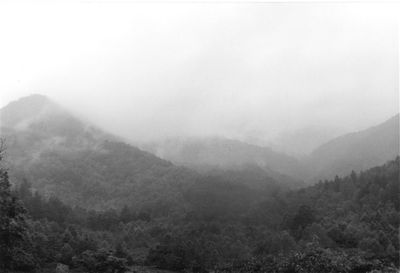 Scenic view of mountains in foggy weather against sky