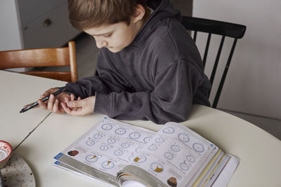 Boy sitting at table and doing homework