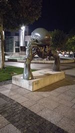 Statue against illuminated city at night