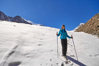 Full length of man standing on snowcapped mountain against sky