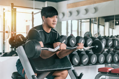 Man lifting barbell while exercising at gym