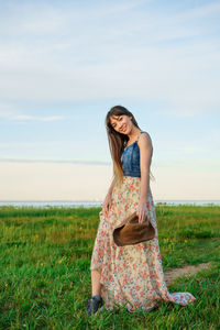 Beautiful young woman in a dress in nature and in a hat