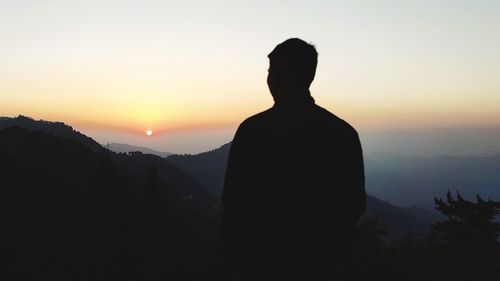 Silhouette man standing on mountain against sky during sunset