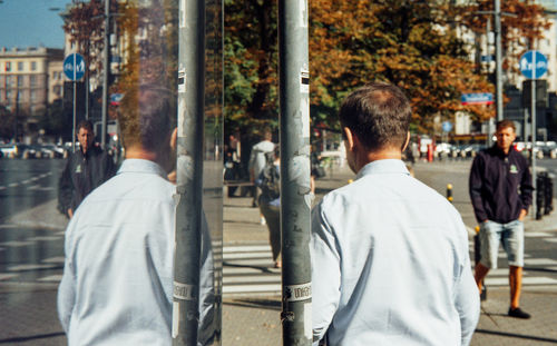 Rear view of men walking on street in city