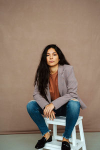 Portrait of woman sitting against wall