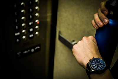 Close-up of woman wearing wristwatch standing in elevator