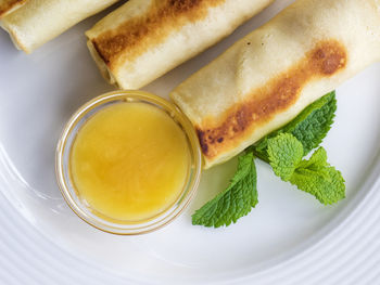 Close-up of pancakes stuffed with curds served with honey in bowl on plate