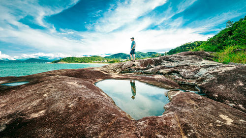 Man standing on rock against sky