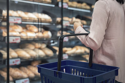 Woman with shopping basket in bakery section of supermarket