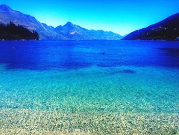 Scenic view of lake and mountains against clear blue sky