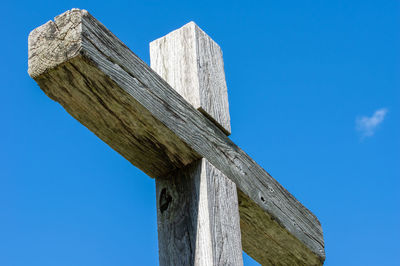 Low angle view of wooden post against blue sky