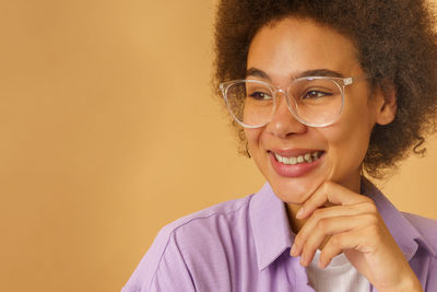 Portrait of young woman against yellow background