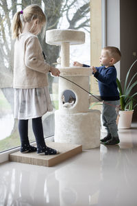 Two kids-brother and sister playing with cat at home