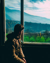 Side view of man looking through window