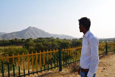 Rear view of man working on mountain against sky