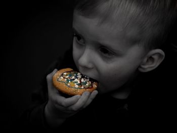 Portrait of boy holding ice cream against black background