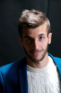 Portrait of young man against black background