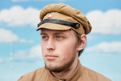 Young man wearing costume looking away against sky