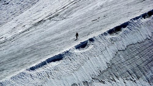 Silhouette man walking on snowcapped mountains during sunny day