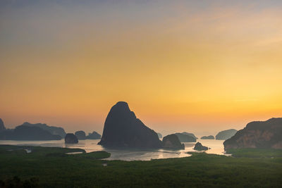 Rocks on sea against sky during sunset